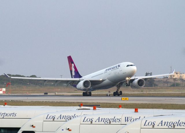 Airbus A330-300 (N382HA) - Early morning arrival on runway 6R, LAX. Airport shuttle buses parked in the foreground.