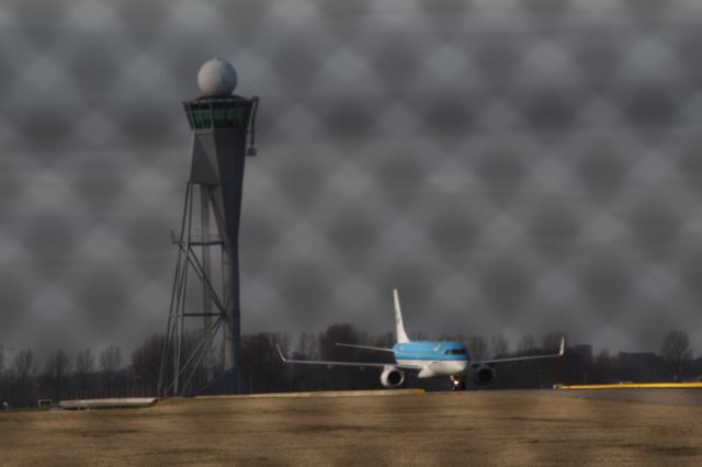 — — - Embraer E190, KLM Cityhopper has landed on the runway and taxiing to the terminal at Schiphol Amsterdam Airport. To the left of the aircraft control tower next to the runway.