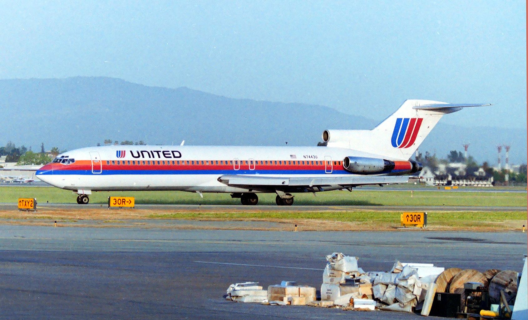 BOEING 727-200 (N7443U) - KSJC - On the ladder at 06:40am, The Chicago 727 is rolling to 30L for departure and someone had cleaned out their hangar with crap all over the place ( some editing) Also note the 94th Aero Squadron Restaurant in the background right side of the 727 on the west side of Runway 30L. Note the 30R directional as this was long long before Runway 30R was extended at SJC. Strange dates here is this jet was delv to United Aug 7 1979, a mere 42yrs plus a week ago, and a month before I started my career job near SJC. Aug 14, 2021 is the posting date today, 42yrs and one week since it was delivered....I have no clue why I ended up with this shot today to post as I am nearing retirement soon with 42yrs plus towards the end of the year...and my all time fav jet...the 727! Who knew?