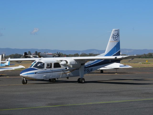 ROMAERO Islander (VH-SLM) - BN2P Islander VH-SLM returning to Rockhampton Airport from a charter flight to Marble Island Queensland Australia. Note Grumman C2 Greyhound in the background operating out of Rockhampton in support of joint Australian and US military exercise Talisman Saber 2013.