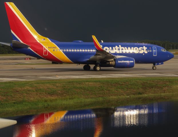 Boeing 737-700 (N451WN) - A slight peek of sunshine provides a reflection on this Southwest 737 taxiing to depart for Raleigh Durham while dark storms lurk just beyond.