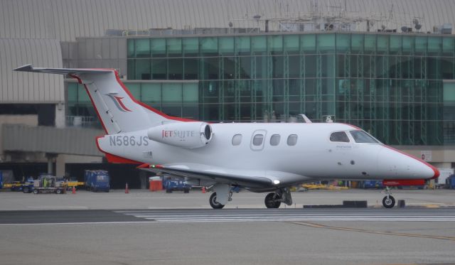 Embraer Phenom 100 (N586JS) - One of Jet Suites Phenoms turning onto runway 20R. The airlines HQ are in nearby Irvine, CA and they use the callsign "redstripe". Looking at the paint job on all of their a/c it is easy to tell why they use that callsign.