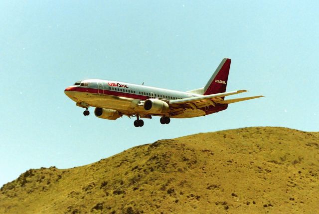 BOEING 737-300 (N375AU) - KRNO - with "Gary Schenauers Rattlesnake Hill" in the background, US Air 737-3 on final for Reno in this appx June 1990-91 view from the old airpark that used to be on the southend of the Runways on the west side. Im sure Gary has stood on the crest of Rattlesnake Hill in this view looking back at the jets! Youll never catch me up there........