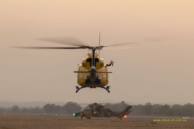 Bell 412 (VH-EPR) - Rescue helicopter 'taxiing' to take off position late in the afternoon with bushfire smoke smothering the sun.  That's a Eurocopter ARH Tiger preparing to leave in the background.