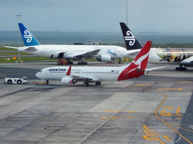 Boeing 737-800 (ZK-ZQB) - Qantas ZK-ZQB taxiing out while Air New Zealand B777-200ER reg ZK-OKB and B777-300ER reg ZK-OKP The Hobbit wait for later duties at AKL on 31 Oct 14.