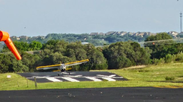 HELIO U-10 Super Courier (N565JS) - Helio taking off from Lakeway Airport. Note the power lines that always provide a memorable approach into this field.