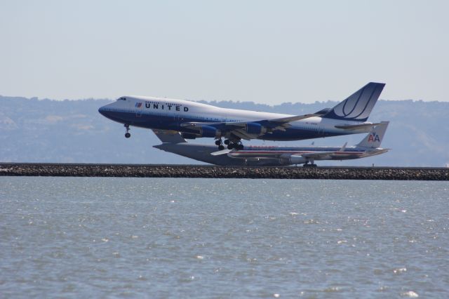 Boeing 747-400 (N182UA) - A UA744 lands on 28L while an AA752 takes off on 28R and a C17 taxis to 28R