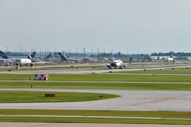 Boeing MD-11 (N624FE) - Three MD-11's moving in this photo. One pushed back for departure on the left. One taking off in the middle, and N624FE taxiing to the FEDEX ramp on the right after having just landed.