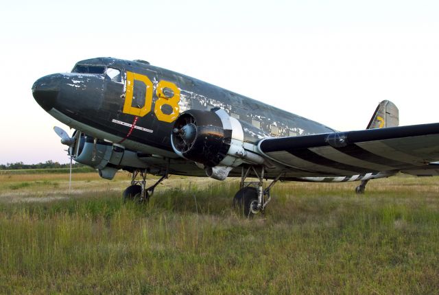 Douglas DC-3 (N12907) - Waiting to feel the vibration of its engines and the wind flowing across its fabric covered control surfaces, this 1945 Douglas DC-3 painted in a 1944 European D-Day invasion paint scheme sits expectantly in a weed covered patch at the south end of  runway 18L in Charlotte, North Carolina USA.