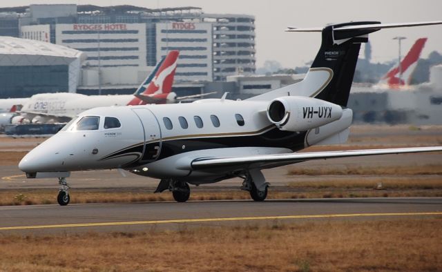 Embraer Phenom 300 (VH-UYX) - I was standing at sheps mound at Sydney when I saw this stunning Embrarer phenom and I got a quick photo which looks really nice, and what is really cool as well is that there is a one world Qantas 747 background.