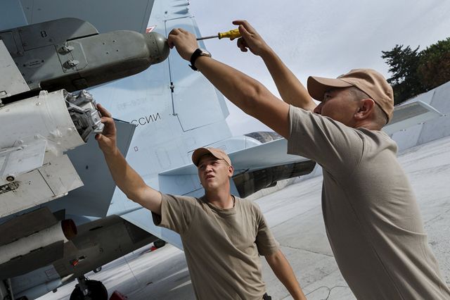 — — - Russian ground staff members work on a Sukhoi Su-30 fighter jet at the Hmeymim air base near Latakia, Syria, in this handout photograph released by Russias Defence Ministry October 22, 2015. (Photo by Reuters/Ministry of Defence of the Russian Federation)