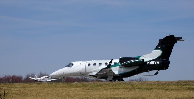 Embraer Phenom 300 (N48VM) - Taxiing to the active runway is this 2015 Embraer Executive Phenom EMB-505 in the Spring of 2019. Also on this VFR day is a Piper Cherokee N3576M that just touched down.