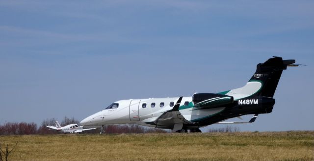 Embraer Phenom 300 (N48VM) - Taxiing to the active runway is this 2015 Embraer Executive Phenom EMB-505 in the Spring of 2019. Also on this VFR day is a Piper Cherokee N3576M that just touched down.