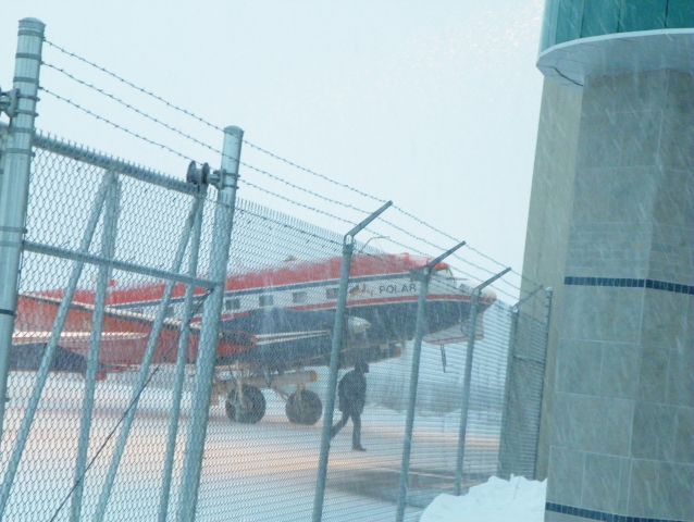 — — - Polar 5 a BT-67 conversion having just landed is being guided to the hangar. You can see the heavy snow and how much she has accumulated since landing here.