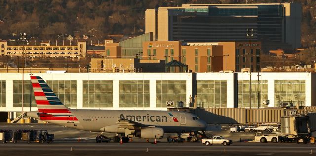 Airbus A319 (N821AW) - The sun has just popped up over the Virginia Range mountains east of the airport and is flooding golden rays of morning light over Americans N821AW at Gate C9 and upon the main terminal building behind AAs Airbus.