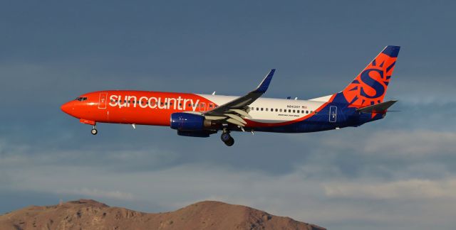 Boeing 737-800 (N843SY) - The setting sun (reflected on the front end of the port engine nacelle as it is just about to descend below the ridge of the Sierra Nevada) casts its final daytime rays on SCX's recently acquired B738 (N843SY) as it passes me on its short final to 34L at the end of a flight from Indianapolis (KIND).