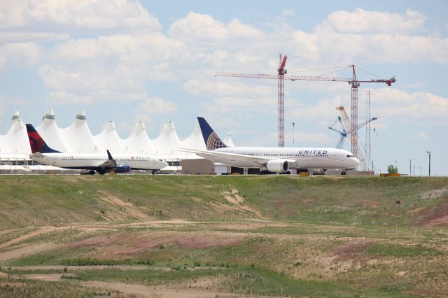 Boeing 787-8 (N20904) - Taxiing past a Delta 737 on 10June2013. DIA terminal and construction cranes for the new hotel in the background.