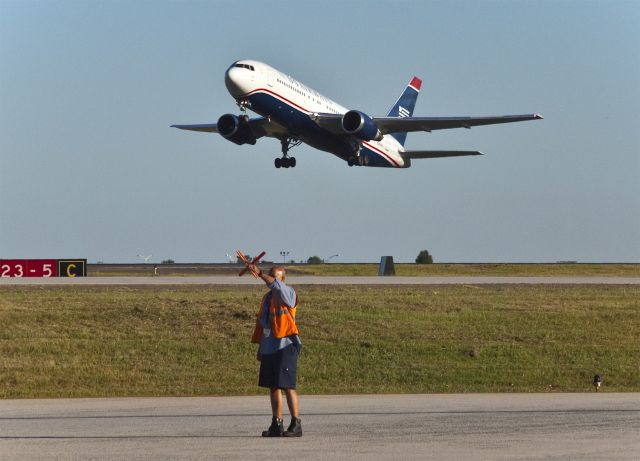 N249AU — - Stop! A ground crew signals the flight crew of an A330 (just out of the picture) to wait while they disconnect the pushback tug and towbar. A Boeing 767 is taking off behind him for Philadelphia. Just 1 1/2 hours before it had arrived from Cancun, Mexico.