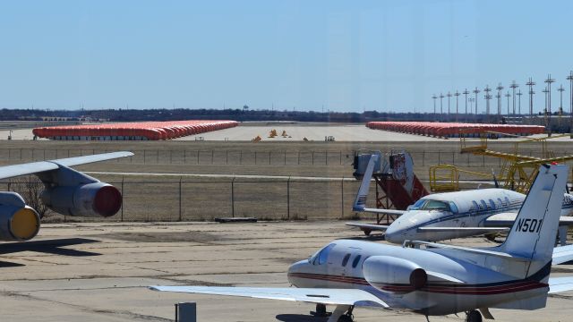 — — - 737 Max fuselages sitting outside of Spirit Aerospace covered in orange tarps.