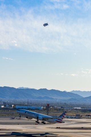 Boeing 777-200 (N756AM) - An American Airlines 777-200 taking off from PHX with a Goodyear blimp in the background on 2/12/23 during the Super Bowl rush. Taken with a Canon R7 and Canon EF 100-400 II L lens.