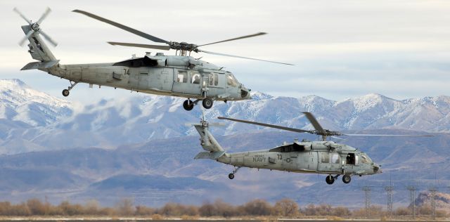 Sikorsky S-70 (16-7865) - Two of the NAWDC Rotary Wing Weapons Schools MH-60S Seahawks (aka: Knighthawks), 167865 (#74) and 167822 (#73), lift away from NAS Fallons taxiway Echo with the snowy Stillwater Range mountains in the distance.br /"73" still displays the "NSAWC" (Naval Strike and Air Warfare Center) acronym title; however, "NSAWC" was redesignated as "NAWDC" (Naval Aviation Warfighting Development Center) last year (2015).  I also observed that some of NAWDCs assigned fixed wing aircraft on the ramp still show NSAWC titling while others now display the NAWDC acronym.br /This photo is my 600th FA gallery post.