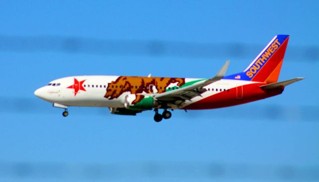 Boeing 737-700 (N609SW) - "California One" passes behind  airport fence on final to 30L.. Got shot while driving by, on my way to another photo assignment