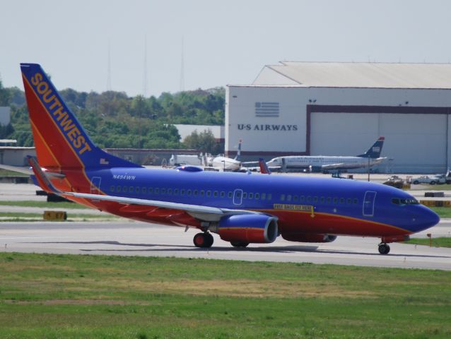 Boeing 737-700 (N494WN) - Inaugural SWA service departing flight at KCLT crossing runway 18C for runway 18R. "Free Bags Fly Here" ... unlike the airline in the background. - 4/14/13