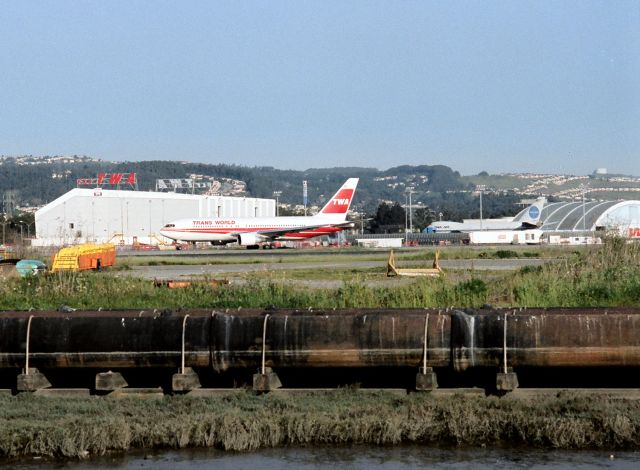 BOEING 767-200 (N602TW) - KSFO- another wide view, note the buildings that had the Airline names on them, including the Pan Am 747 in the distance, the Pan Am building was torn down pre 1999 for the new SFO Intl Terminal. Note the hint of a Western 737 or 727 peeking into the right of the photo. The housing tracts in the foothills west of SFO are all full now and covered in trees or shrubs. Hard to belive this was 24 years ago!