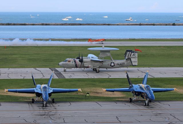 YAKOVLEV Yak-55 (N921GR) - Mark Sorenson- Tito- in his YAK-55, Twin Tiger Salute, on takeoff roll as an E-2C+ Hawkeye taxies to park behind two US Navy Blue Angels Boeing F/A-18C Hornets (163708/5 & 163444/6) parked on the ramp at Burke Lakefront Airport during the Cleveland Air Show on 2 Sep 2018.