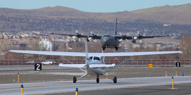 Cessna Skyhawk (N752DW) - As one of Great Basin's Cessnas (N752DW) taxies north on Charlie with a student pilot at the controls, a Nevada ANG C-130H Hercules (92-0548) is about to pass by the Cessna as it completes its s/final approach to Runway 16L.