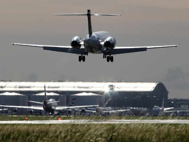 — — - A Blue B717-200 catches the suns strong reflections of the runway as it approaches runway 027R at London Heathrow.