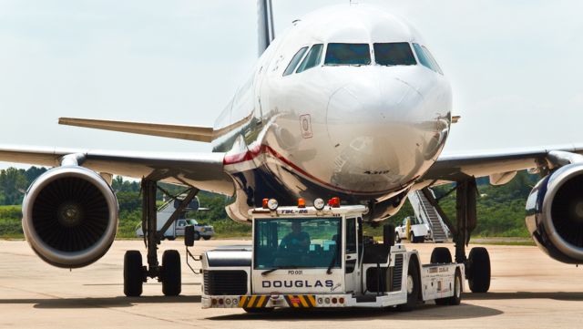 Airbus A319 (N758US) - A Douglas "Super Tug" delivers a US Airways A319 to the hangar for maintenance. This tug requires only one driver and actually lifts the nose gear of the aircraft off the ground using powerful hydraulics. It is very safe and maneuverable.