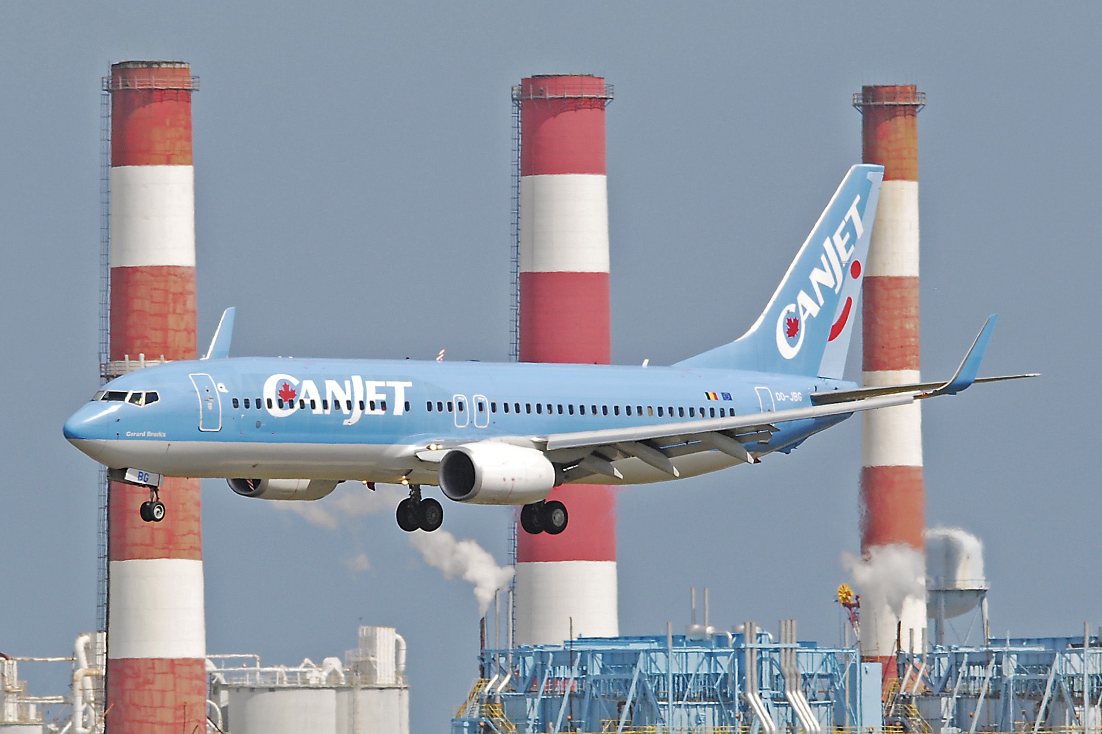 Boeing 737-800 (OO-JBG) - Canjet on approach  to 27R at KFLL with landmark smokestacks in the background. Feb 25, 2011