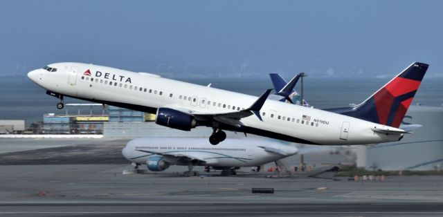 Boeing 737-900 (N919DU) - KSFO March 13 2020 from the SFO tram station one of my last Airliner photos this year - Delta 900 screaming off 28L for ???