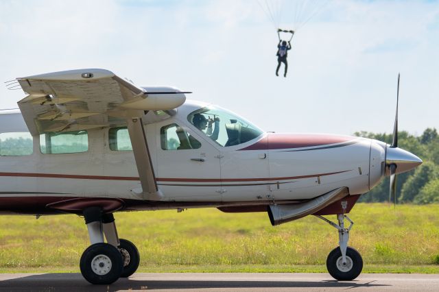 Cessna Caravan (N509JE) - Cessna Caravan jump pilot holds on the taxiway for parachute traffic at KCKZ, and gives signs of encouragement to a nearby skydiver