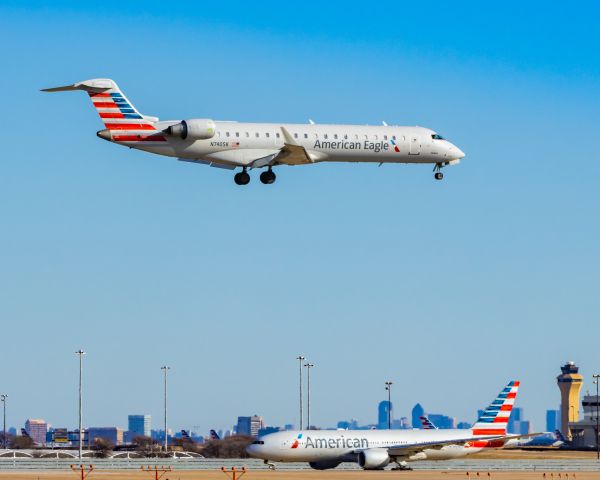 Canadair Regional Jet CRJ-700 (N740SK) - SkyWest CRJ700 landing at DFW while an American Airlines 777-200 taxis on 12/25/22. Taken with a Canon R7 and Tamron 70-200 G2 lens.