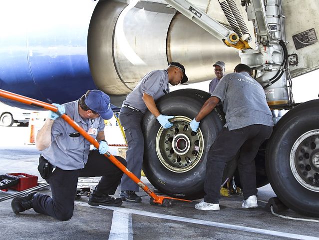 BOEING 767-200 (N245AY) - A US Airways Boeing 767 gets a new #3 main tire on a quick turn around  en route to Paris. Displaying the teamwork and confidence that comes from years of training and working on the big jets, AMTs* Joe, Kurt, Sterling and Sparky make a tough job look easy! Joe is sighting down the axle to line up the wheel bearing while Sterling is giving directions to align the wheel to the brake assembly. Everything has to be perfect to mount the wheel. Good work men!    *AMT: Aircraft Maintenance Technician - FAA licensed Airframe & Powerplant Mechanic.