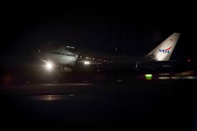 BOEING 747SP (N747NA) - NASA's one-and-only 'SOFIA' B747-SP (callsign NASA-747) flying infrared telescope observatory lifting off Runway-20 tonight at Christchurch International Airport for a night flight over the Southern Ocean south of New Zealand. I quickly shot over to the airport after work with my camera gear to see her depart on her latest mission over New Zealand. I heard the crew on 'Ground' so got ready near the runway intersection outside the fire rescue station. ATC had a Dash-8 on short final popping out of the soup about 8 miles downwind with a request to slow down to minimum approach speed so as to let SOFIA get airborne. This photo as can be seen, was shot in the dark with ISO at 6400, 1/45s, f8 at 160mm. Processed lightly in Lightroom to get rid of the noise.