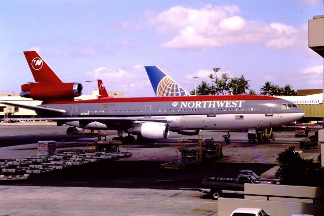 McDonnell Douglas DC-10 (N221NW) - PHNL- July 1998 shows Northwest DC-10 being readied for the next flight - the Continental Micronesia 747 behind this jet was a surprise for me. The Honolulu open air terminal and walkways were a real treat when visiting - no windows to obscure the view. We also went to the top floor of the parking structure for great views, and we had a Tower Tour at 1pm - the cargo cart traffic can be a real pain as they are perfectly "timed" to drive into view when taking photos - be aware! 35mm Color slide converted.