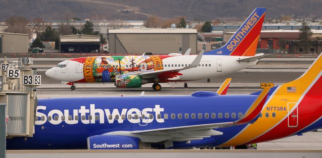 Boeing 737-700 (N945WN) - Southwests Florida One (N945WN) is seen beyond a company fleetbird as it heads away from the Southwest apron at Reno Tahoe International and rolls north on Alpha toward runway 16R.