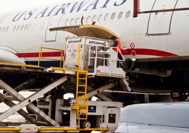 Airbus A330-200 (N281AY) - Loading the last freight container in the pouring rain.