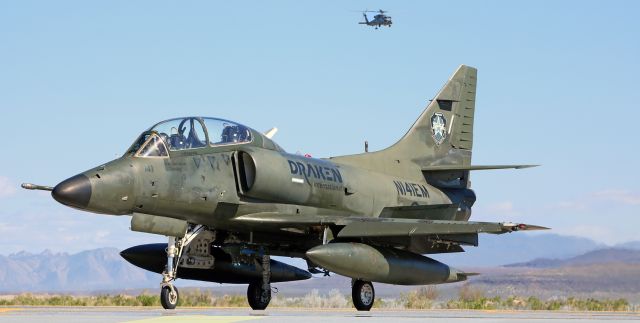 SINGAPORE TA-4 Super Skyhawk (N141EM) - Draken International's N141EM, a TA-4 Skyhawk, awaits tower pernmission to line up and launch on 31L as a Seahawk returning from a training sortie comes overhead to land at Hangar 7.