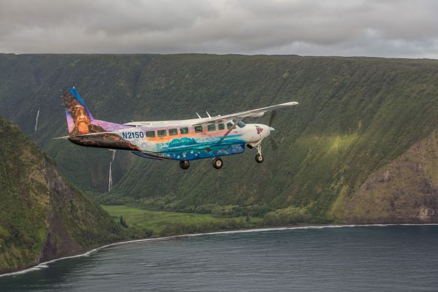 Cessna Caravan (N2150) - Big Island Air flies around the island of  Hawaii in this colorful Grand Caravan....shown here crossing the Waimea Vallley iver the blue Pacific Ocean