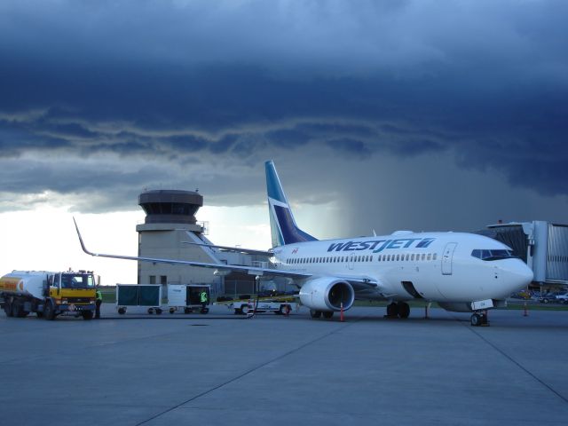 Boeing 737-700 — - WestJet Boeing 737-700 on the ramp at Fort McMurray Airport, Alberta, Canada with a storm brewing to the west.