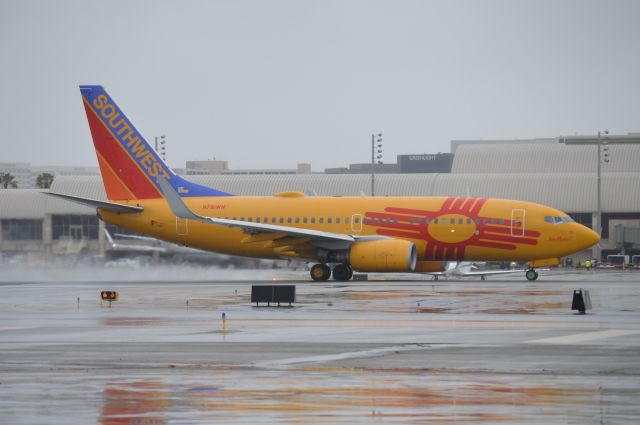 Boeing 737-700 (N781WN) - Southwests "New Mexico One" starting its takeoff roll on a wet runway 20R. The rain was off and on all day and at some points the visibility was so bad that eve at this short range the shot would have been obstructed. Thankfully though, the rain let up just before this special paint left. The quality isnt optimal as I was still figuring out my camera settings in these conditions but I felt that it was still good enough to upload.