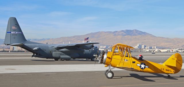 NAVAL AIRCRAFT FACTORY N3N (N4009A) - "Air Force meets Navy" is an appropriate title for this photo of a Nevada ANG "High Rollers" C-130H Hercules (92-0548) taxiing north in the background as the Commemorative Air Force High Sierra Squadrons Naval Aircraft Factory N3N-3 (N4009A) taxies south on the Atlantic Aviation ramp.