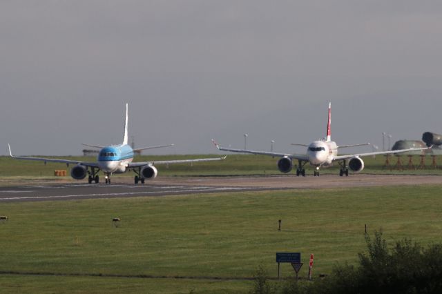 Embraer ERJ-190 (PH-EZV) - Smaller and bigger answers to the same problem.  PH-EZV lined up ahead of HB-JBH for departures to Amsterdam and Zurich respectively.  Sorry for the heat haze.