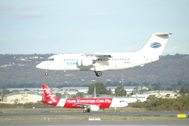 British Aerospace BAe-146-200 (VH-NJG) - Cobham aircraft landing on Rwy 03 on at Perth Intl Airport while a Air Asia Indonesia taxis towards runway 03 on taxiway C