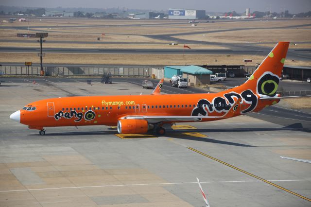 Boeing 737-800 (ZS-SJA) - Snapped at 12:41 on Thursday 1 August 2019 on a rather murky day in Johannesburg (FAOR), this bright Mango Boeing 737-8S3 fleetbird had recently arrived from Durban (FALE), and making her way to the bay. *Click Full*