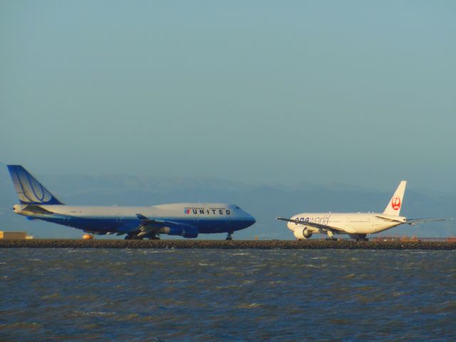 Boeing 747-400 — - Rush Hour with two heavies preparing for takeoff as the sun sets at SFO Airport, Millbrae California. Very windy day as the waves can tell you!